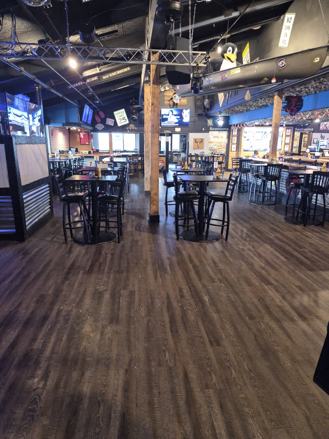 The main room at Canton Icehouse with high-top tables, wood floors and a canoe suspended above the seating